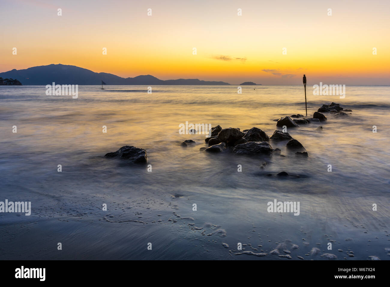 Romantischen sonnenaufgang Stimmung im Stillen Ozean Wasser und Steine am Strand Stockfoto