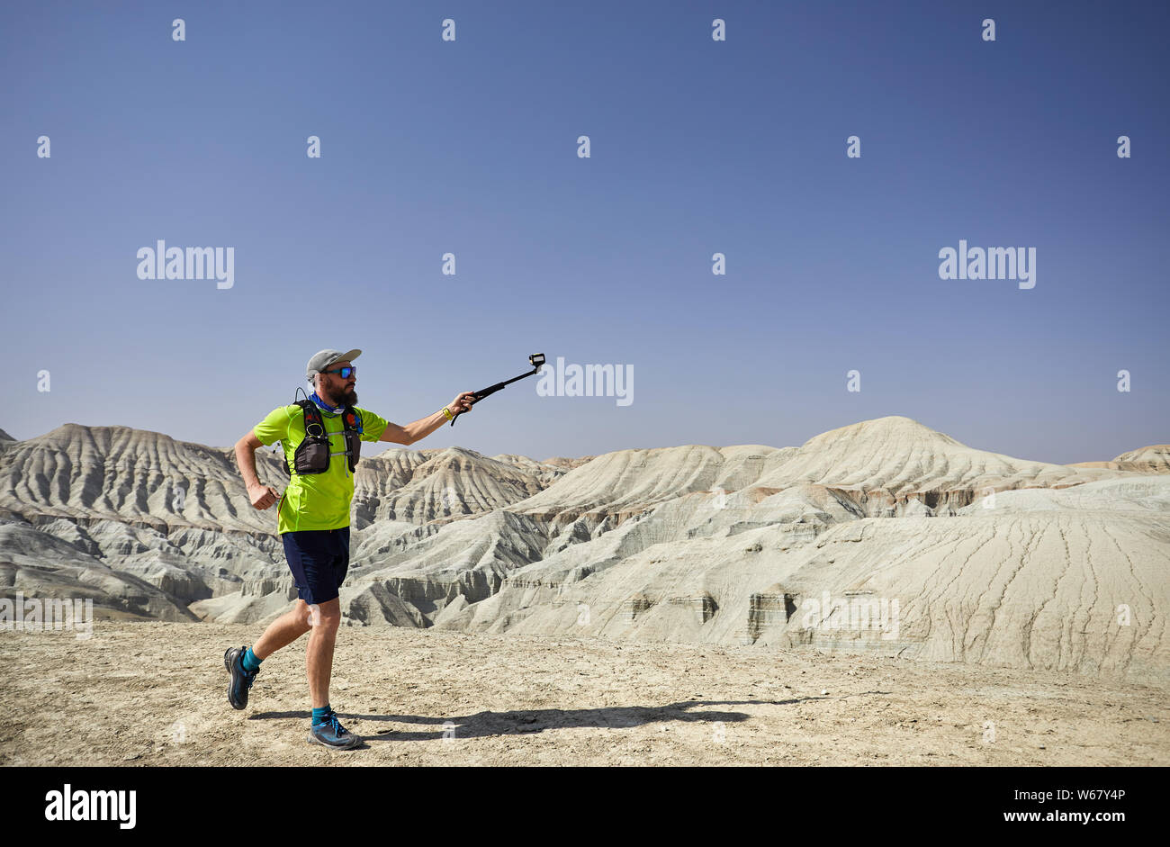 Runner Athlet mit Bart, die auf der Weißen Berge in der Wüste mit Action Kamera Stockfoto