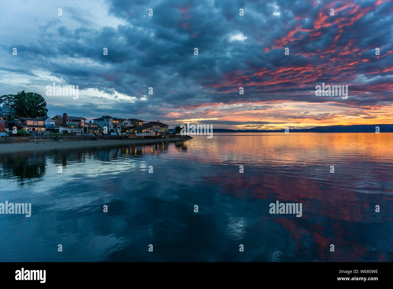 Die Wolken hängen am Himmel, wie die Sonne hinter den Olympic Mountains im Armaturenbrett, Washington. Stockfoto