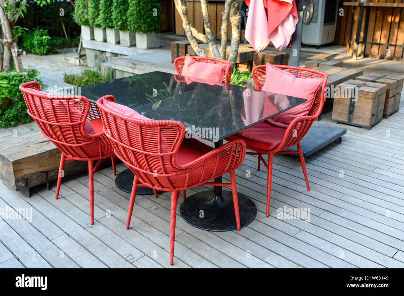 Marmor Esstisch mit roten spinnen Stühle mit Kissen auf hölzernen Terrasse Stockfoto