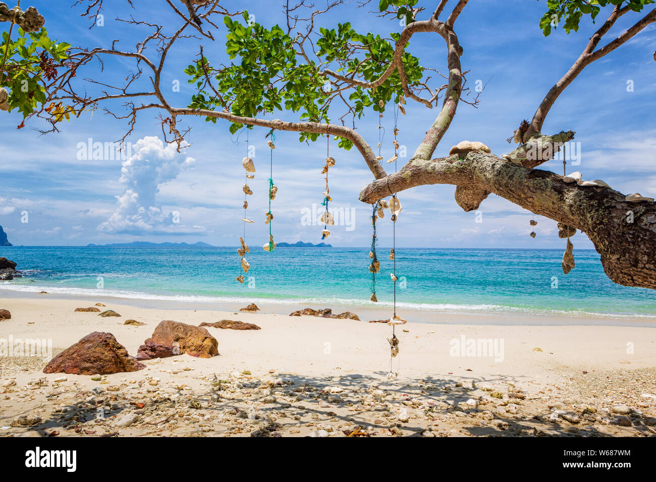 Leerer Traum Strand mit weißem Sand auf der Insel Koh Ngai, Thailand. Muscheln hängen von einem Ast auf eine Zeichenkette. Stockfoto