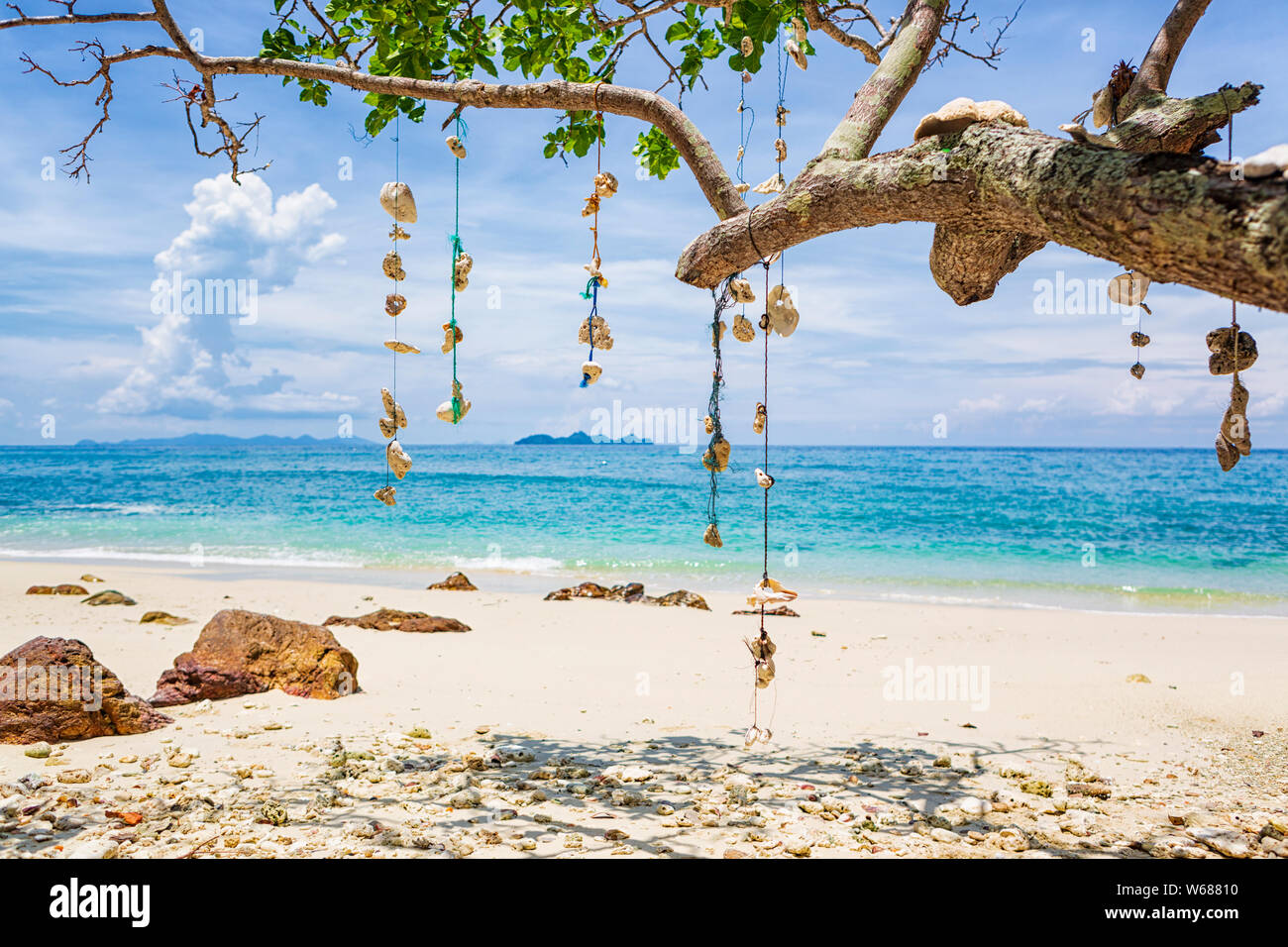 Leerer Traum Strand mit weißem Sand auf der Insel Koh Ngai, Thailand. Muscheln hängen von einem Ast auf eine Zeichenkette. Stockfoto