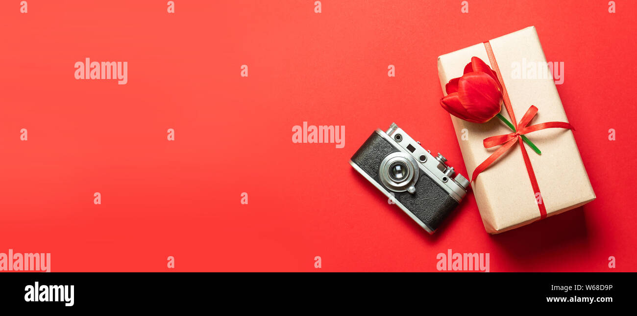 Alten Retro Vintage Kamera, Geschenkbox mit roter Schleife auf rotem Hintergrund, Ansicht von oben flach mit kopieren. Stockfoto