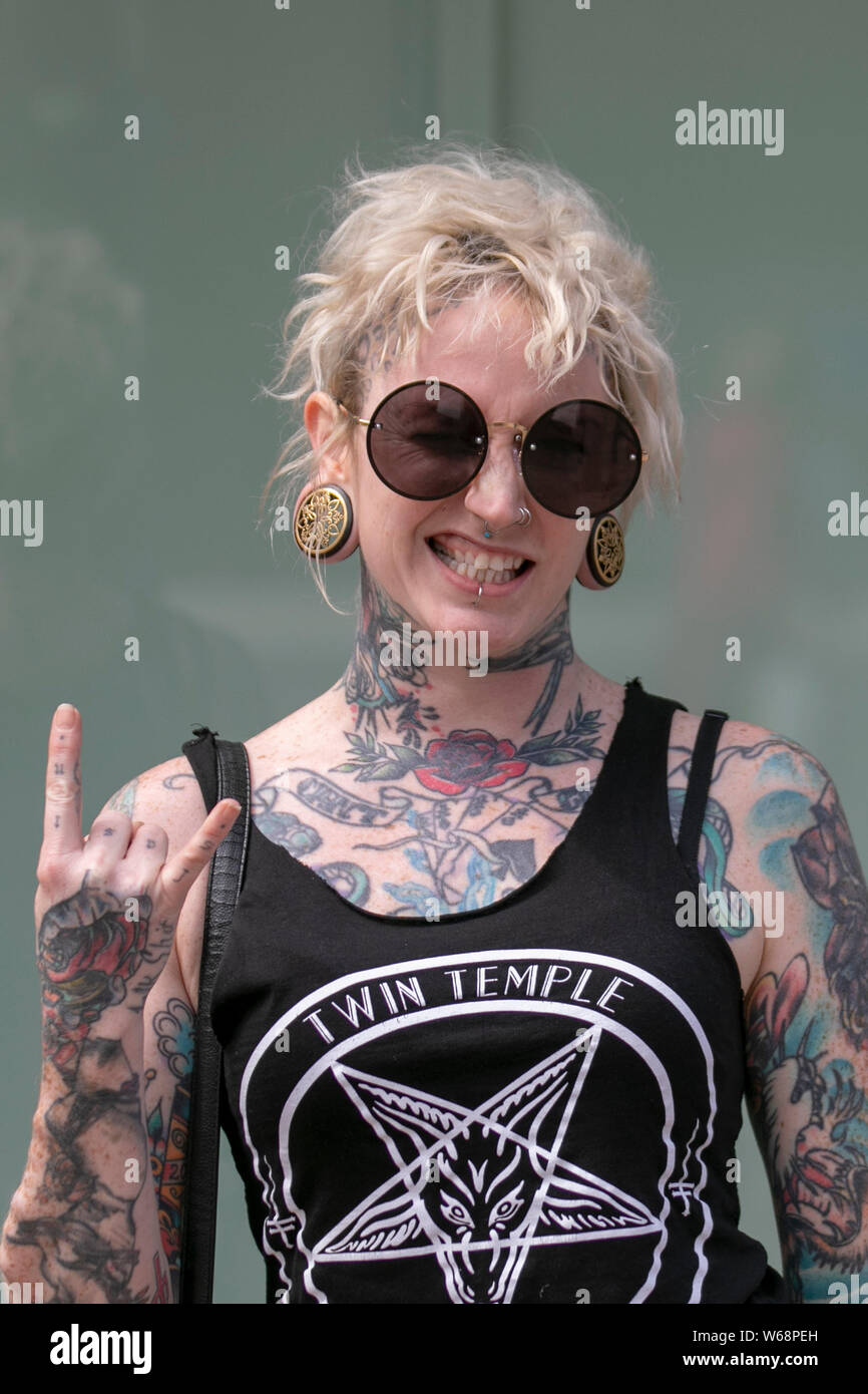 Weibliche Körper-Tattoos; Bobbie mit zerzaustem welligen blonden lob-Haarschnitt aus Texas, Mitglied der Rock Band beim Rebellion Festival, dem größten Punk-Festival der Welt in Blackpool. Anfang August finden in den Winter Gardens von Blackpool zahlreiche Punk-Bands statt, die 21. zum Rebellion Festival eingeladen wurden, das Tausende von Touristen in das Resort zieht. An über 4 Tagen im August treffen sich in Blackpool die besten taoed Punk zu diesem gesellschaftlichen Event des Jahres mit 4 Tagen Musik auf 6 Bühnen mit Massen von Bands. Stockfoto