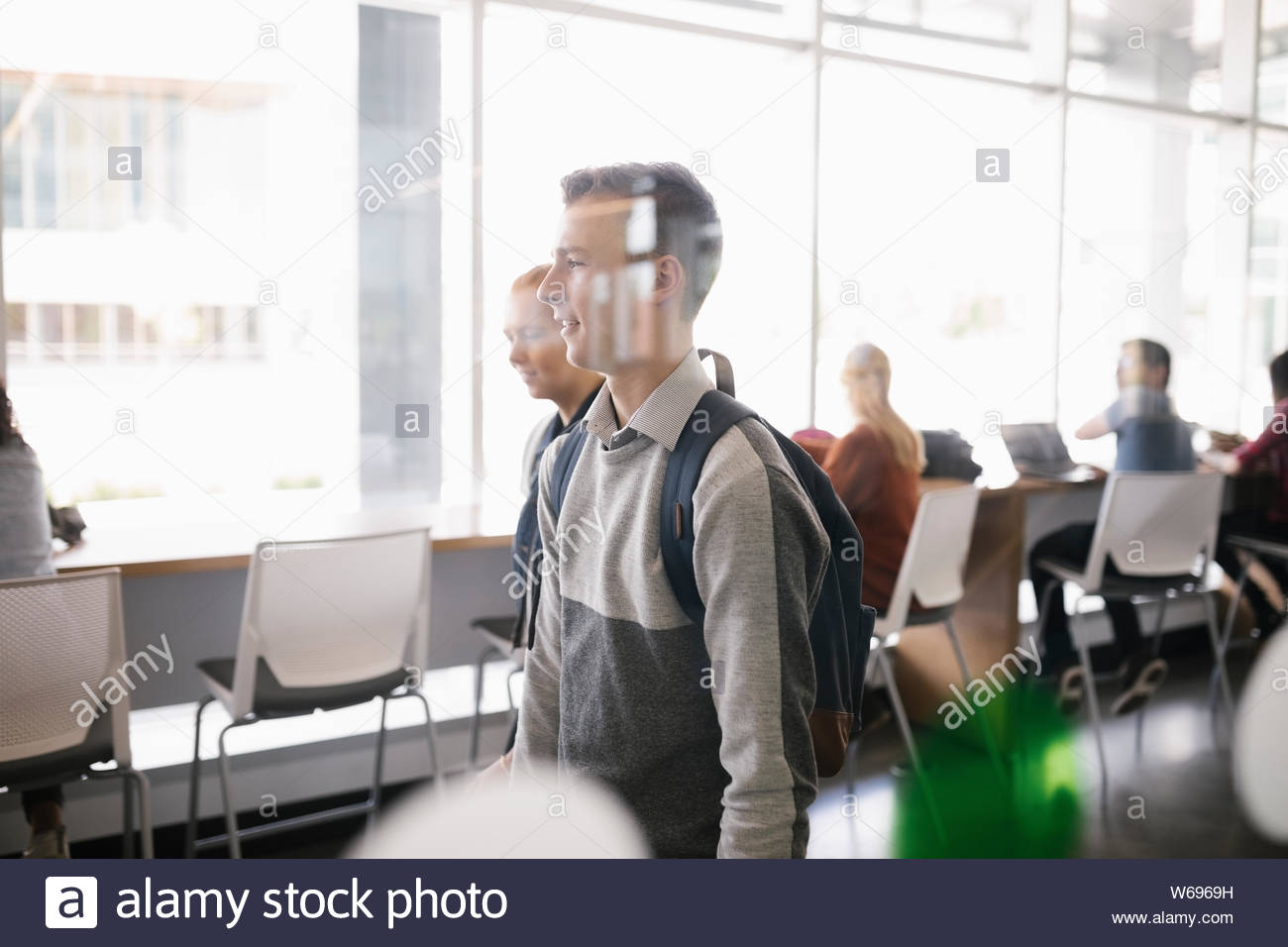 Männliche Kursteilnehmer zu Fuß hinter Glas in der modernen Universität Stockfoto
