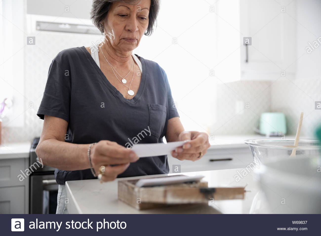 Ältere Frau auf Rezept in der Küche auf der Suche Stockfoto