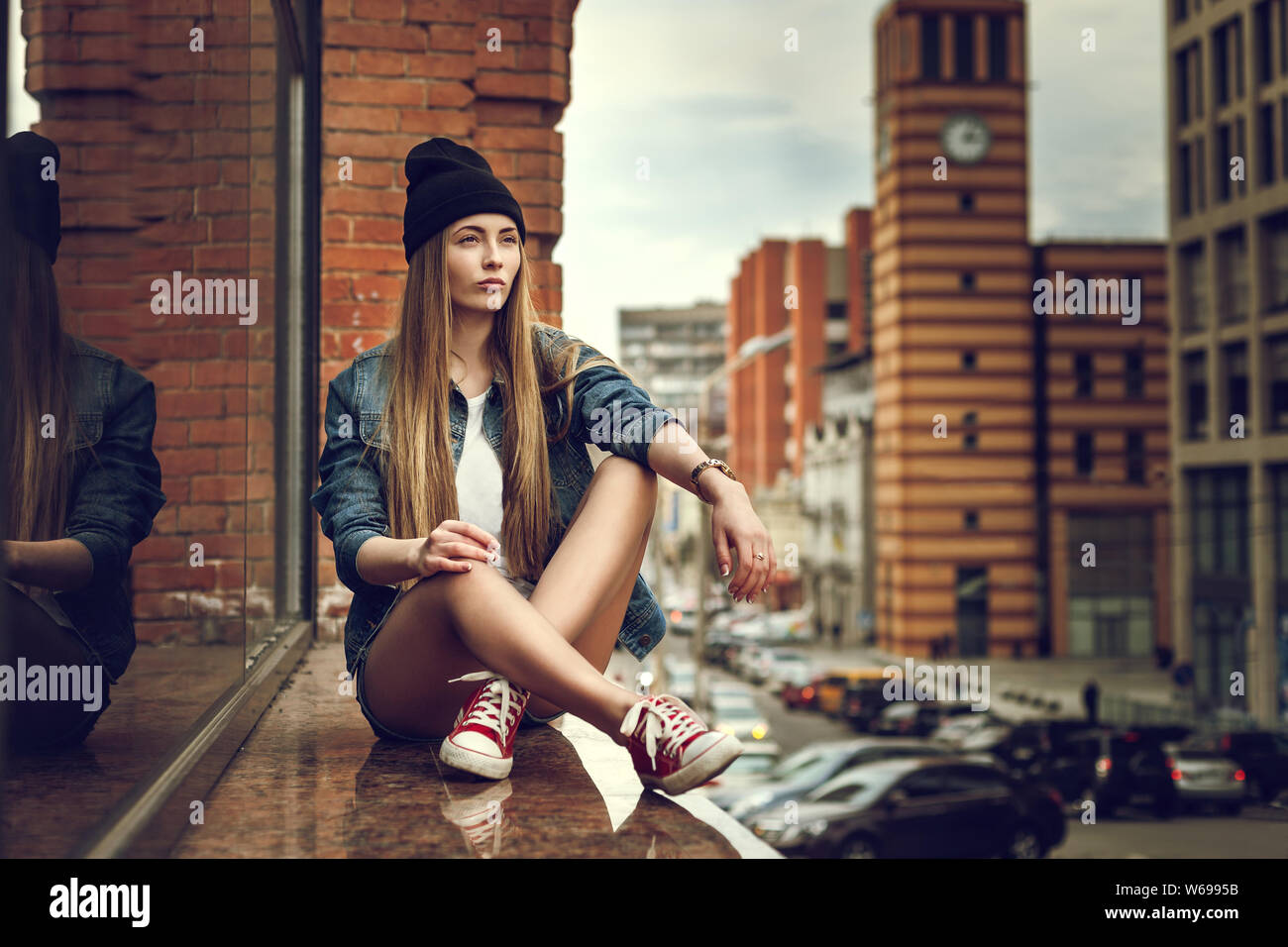 Outdoor Lifestyle Portrait von hübschen jungen Sitzendes Mädchen, tragen in Hipster swag grunge Style im städtischen Hintergrund. Retro Vintage getonten Bild, Film simula Stockfoto