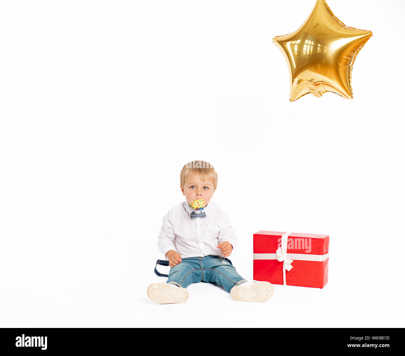 Cute little boy, Jeans und Hemd, stehen in der Nähe des heutigen und weht im Geburtstag tune. Gold Ballon, form Sterne. auf weißem Hintergrund Stockfoto