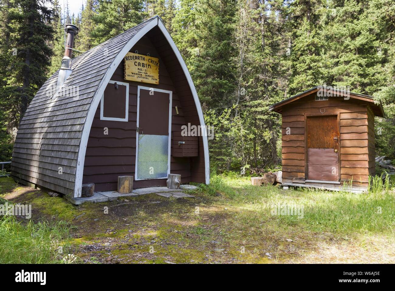 Old Backcountry Ranger Wood Blockhütte und Outhouse in Forest Meadow Clearing. Wandern Am Redearth Creek, Banff National Park, Canadian Rocky Mountains Stockfoto