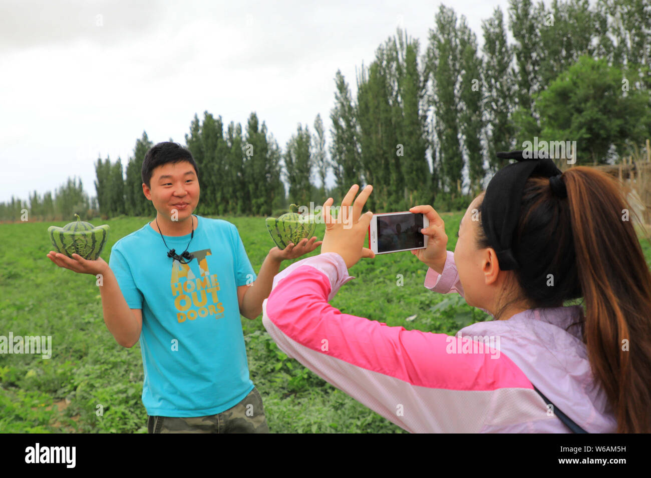 Eine touristische Posen für Fotos mit Wassermelonen mit der Form des sycee in Bohu County, Bayingolin Mongolischen Autonomen Präfektur, Nordwesten Chinas Xi. Stockfoto