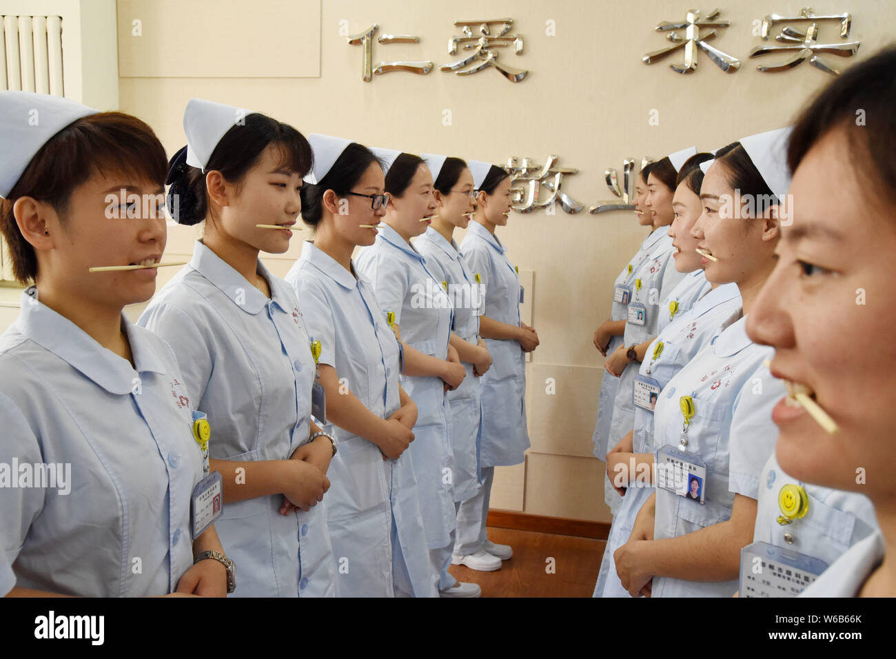 Weibliche Krankenschwestern biss Stäbchen lächelnd für Patienten, die an der Praxis der Welt Lächeln Tag in einem Krankenhaus in Handan Stadt zu markieren, der Norden der Provinz Hebei, China Stockfoto