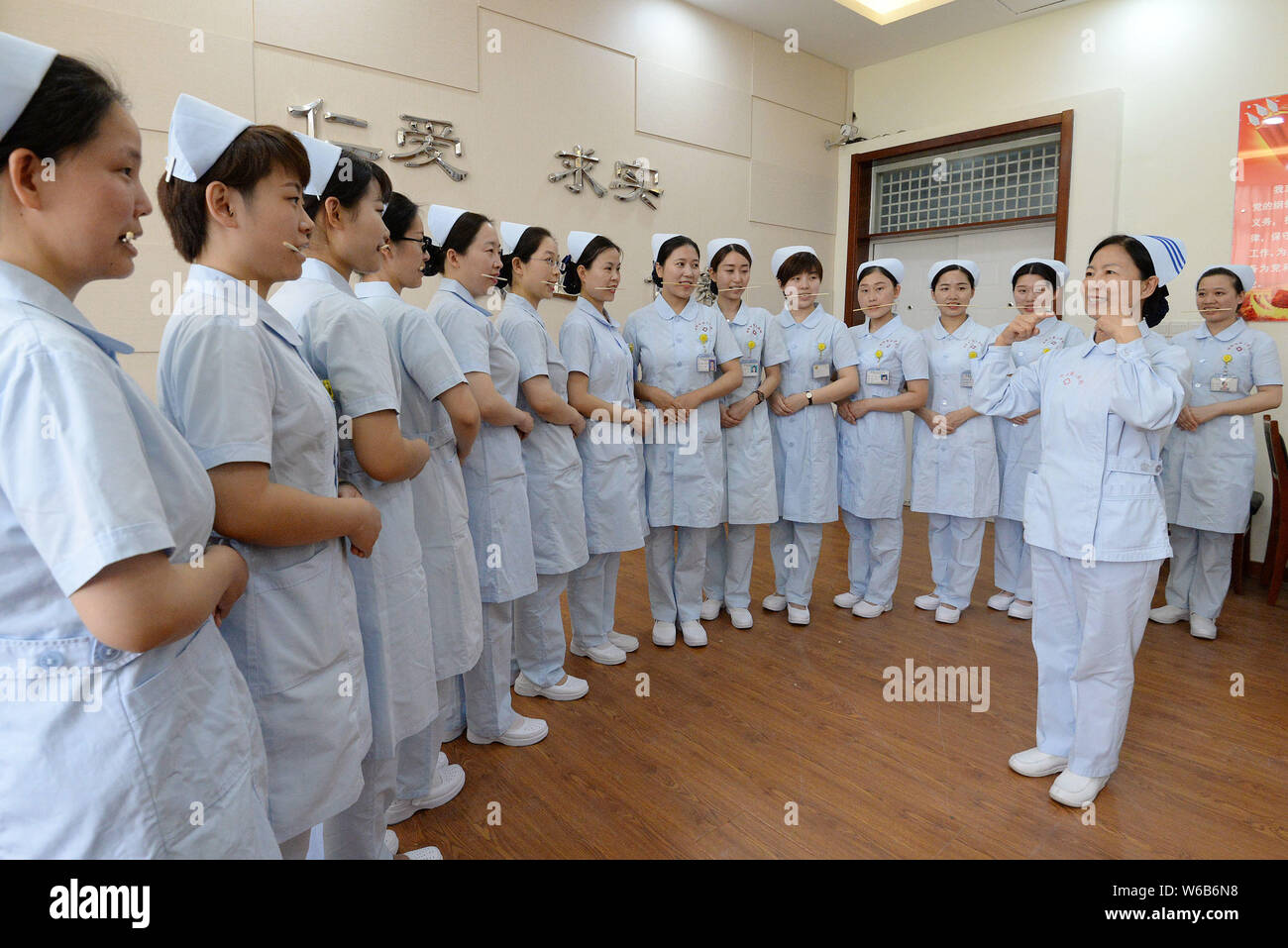 Weibliche Krankenschwestern biss Stäbchen lächelnd für Patienten, die an der Praxis der Welt Lächeln Tag in einem Krankenhaus in Handan Stadt zu markieren, der Norden der Provinz Hebei, China Stockfoto