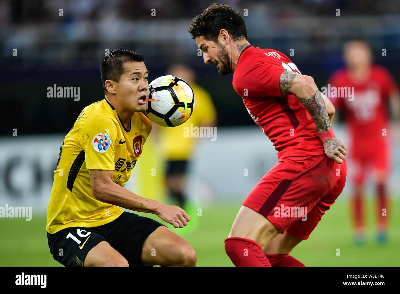 Brasilianische Fußballspieler Alexandre Rodrigues da Silva, bekannt als Pato, rechts, der von China Tianjin Quanjian kickt den Ball einen Pass gegen Huang zu machen Stockfoto