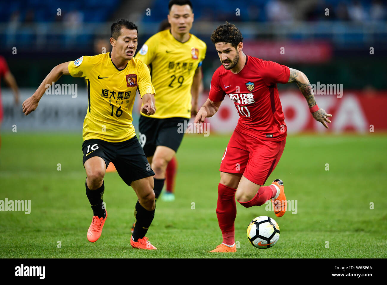 Brasilianische Fußballspieler Alexandre Rodrigues da Silva, bekannt als Pato, rechts, der von China Tianjin Quanjian kickt den Ball einen Pass gegen Huang zu machen Stockfoto