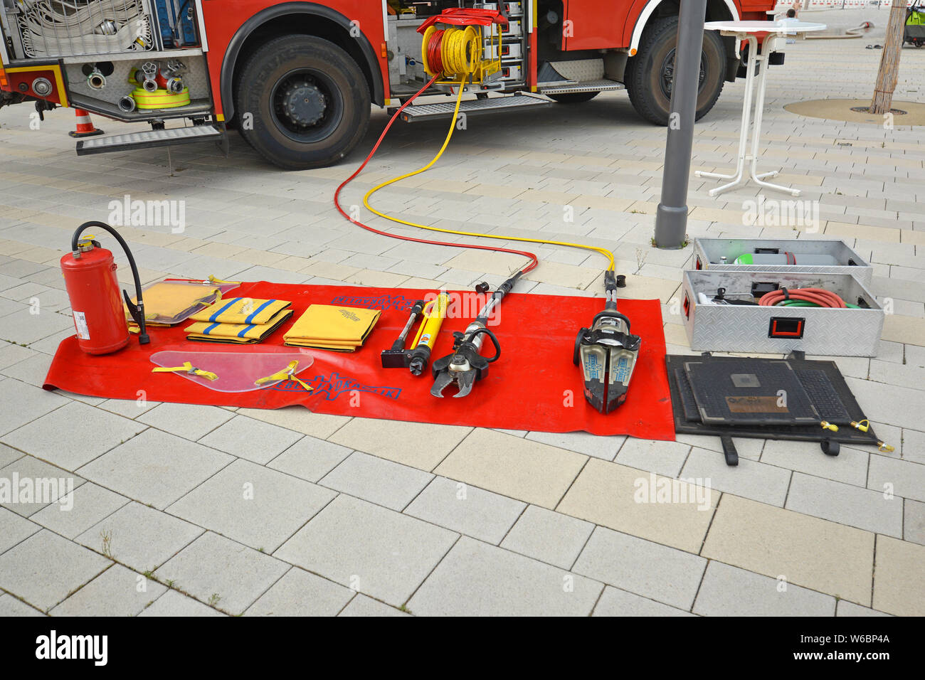 Tools wie Brandbekämpfung Löschmittel Decke, hydraulische Rettungs Cutter oder Feuerlöscher von fire truck auf Anzeige auf rot Decke auf dem Boden Stockfoto