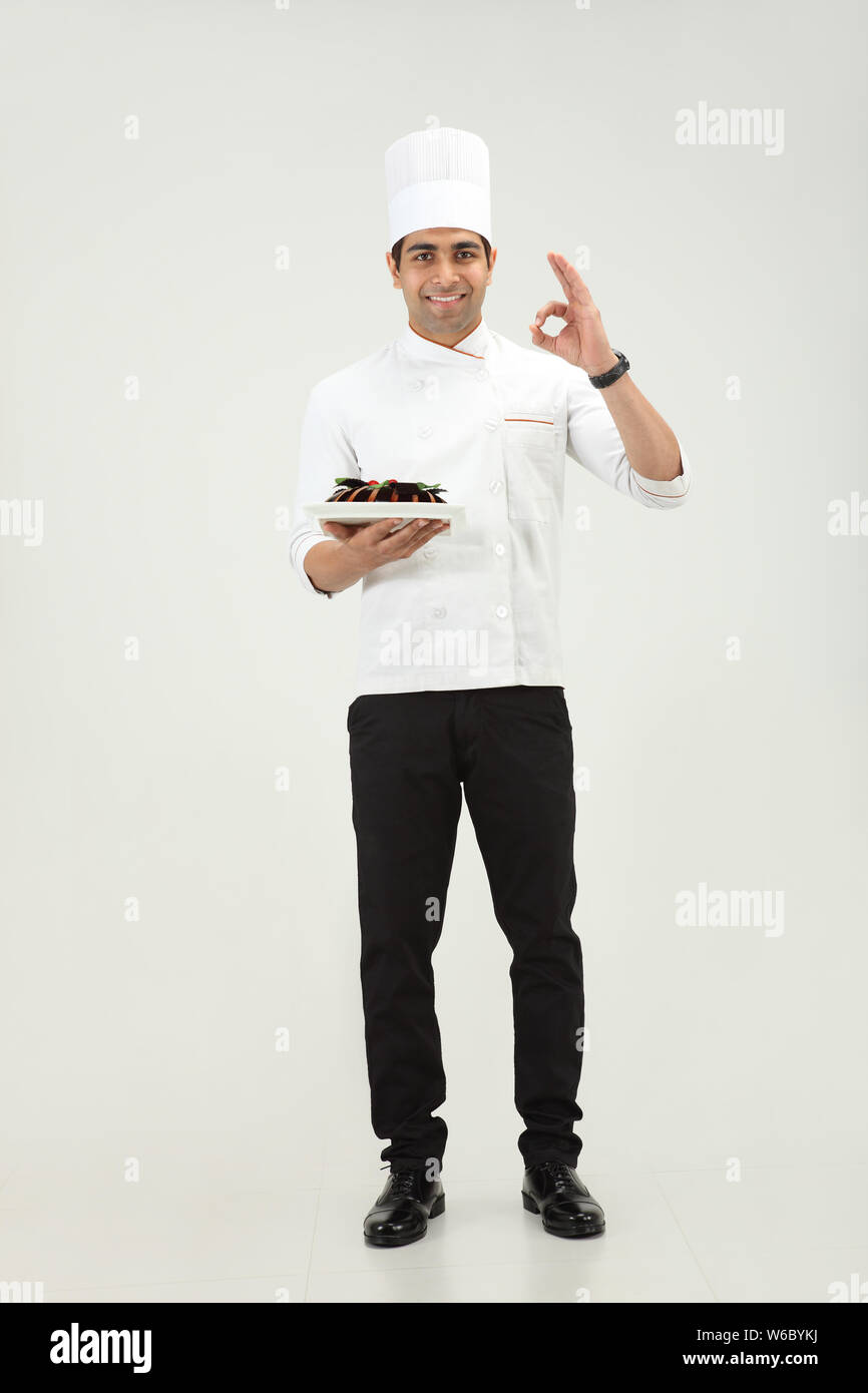 Der Koch hält einen Kuchen und zeigt das Schild OK Stockfoto