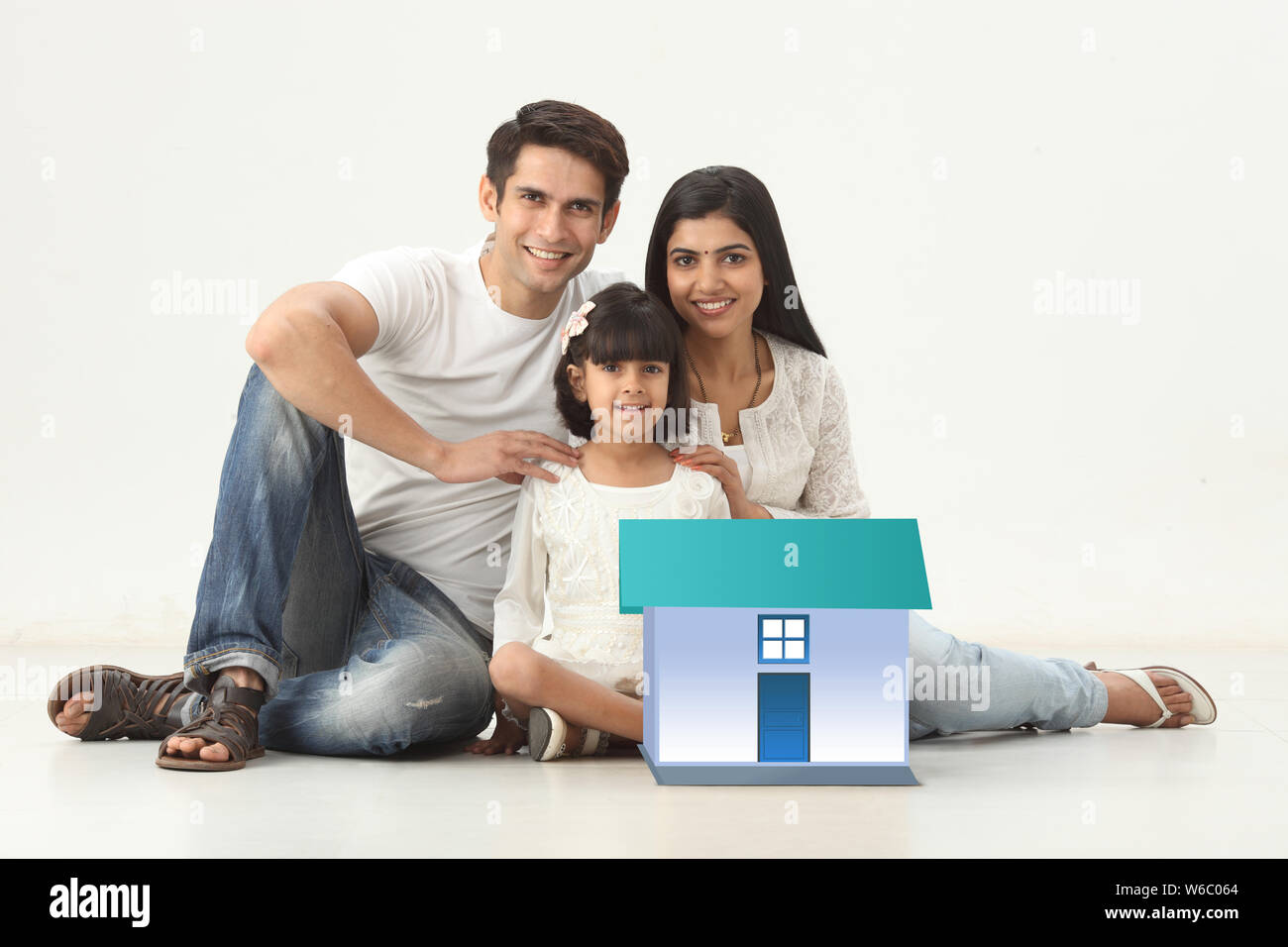 Familie sitzt mit Modell von Traumhaus Stockfoto