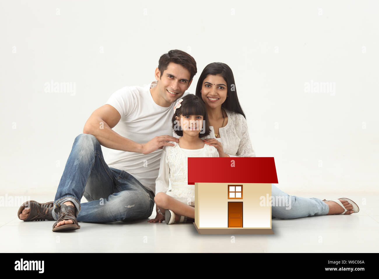 Familie sitzt mit Modell von Traumhaus Stockfoto