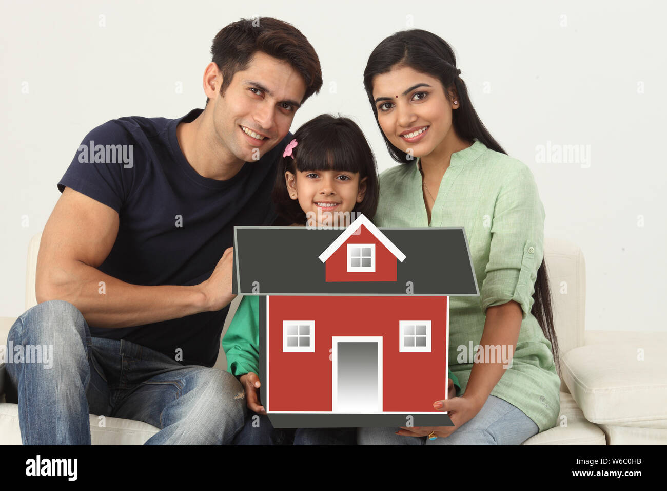 Familie sitzt auf einer Couch mit Modell von Traumhaus Stockfoto