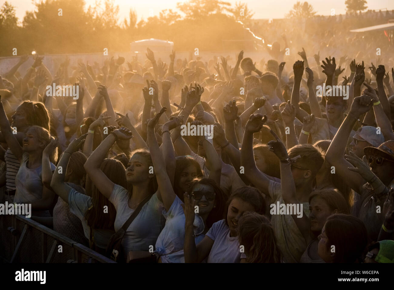 Hunderte von jungen Menschen feiern Holi, das Fest der Farben, bei Sonnenuntergang Stockfoto