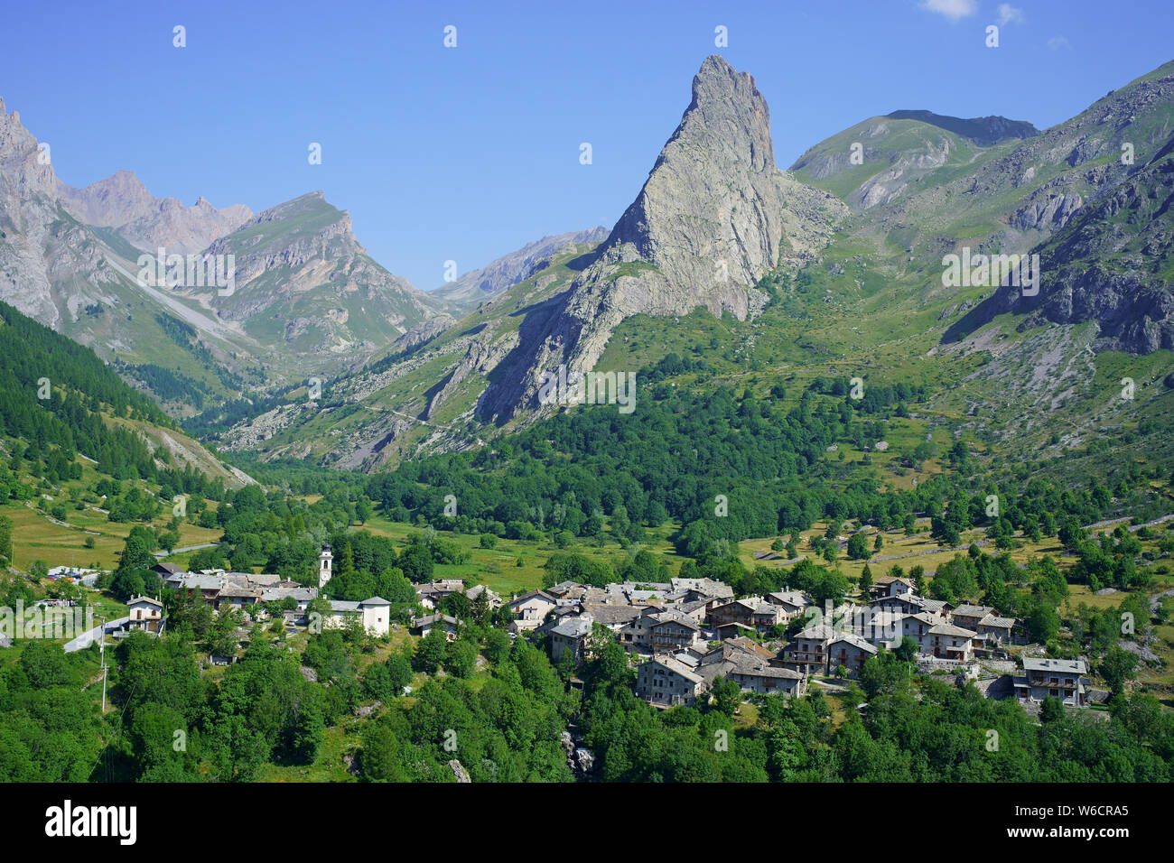 LUFTAUFNAHME. Letztes Dorf (alt.: 1650m) des oberen Maira-Tals und dessen markante 'Rocca Provenzale' (alt.: 2451m). Chiappera, Piemont, Italien. Stockfoto