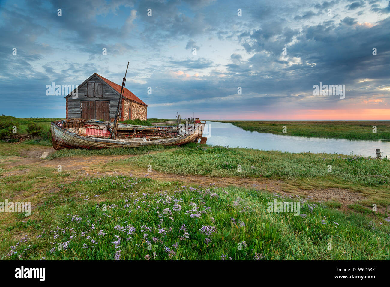 Sommer Sonnenaufgang über einem alten Kohle Scheune und Fischerboot an thornham an der nördlichen Küste von Norfolk Stockfoto