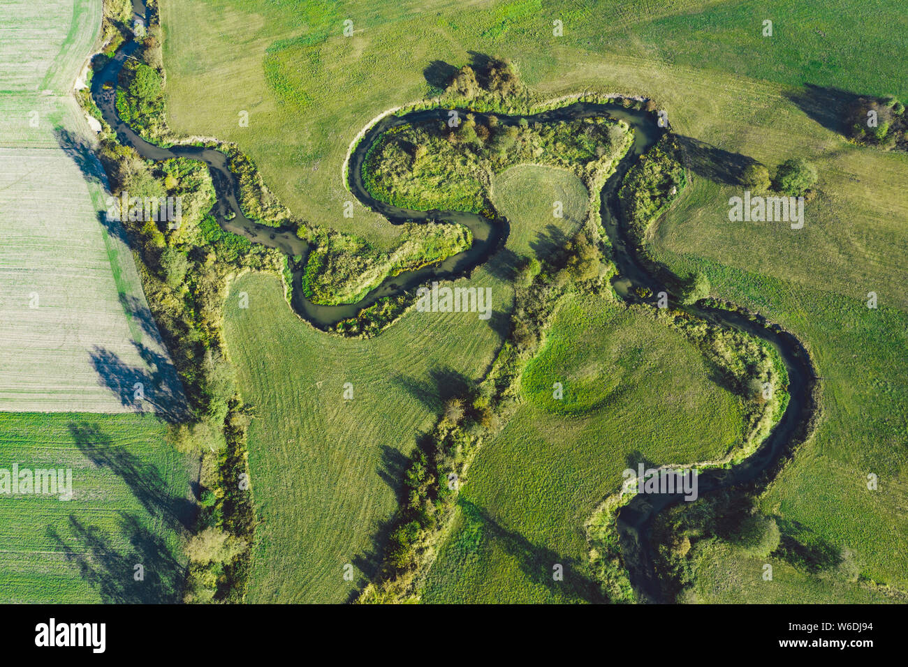 Ein gewundener Fluss umgeben von grünen Wiesen Stockfoto