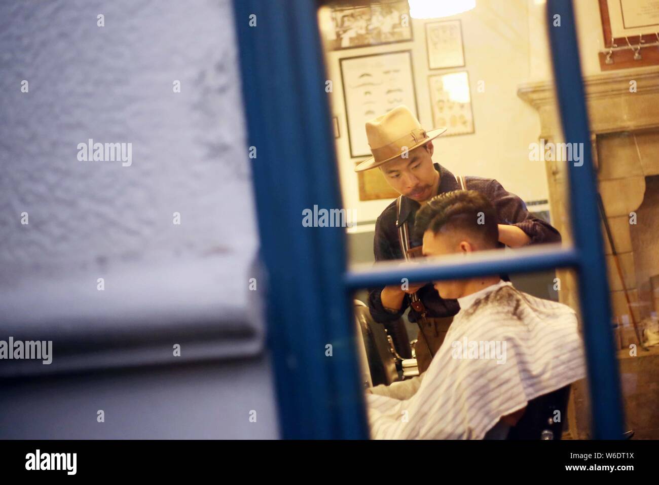 Der Besitzer eines Shanghai-based Barbershop, BarberShop nur auf vintage Herren- Stil Haarschnitte arrangiert ein retro Frisur für einen Kunden in Stockfoto