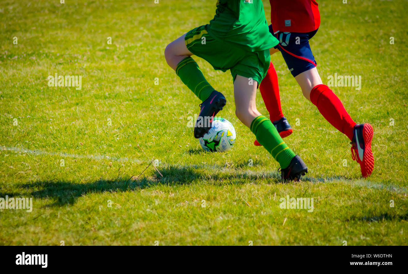 Zwei gegnerische Spieler auf der Jagd nach einem Fußball. Die Athleten in dem Bild sind 14 Jahre alter Junge Fußballspieler. Dieser Schuss fängt sie beide in Aktion. Stockfoto