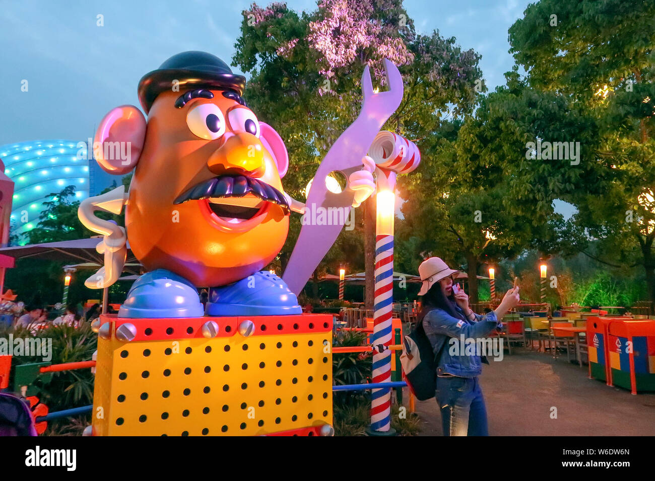 Ein Besucher stellt für Fotos mit einer Skulptur von Frau Potato Head, ein Charakter der animierte Film Pixars "Toy Story", an der 7. Thematische Land, Disney Stockfoto