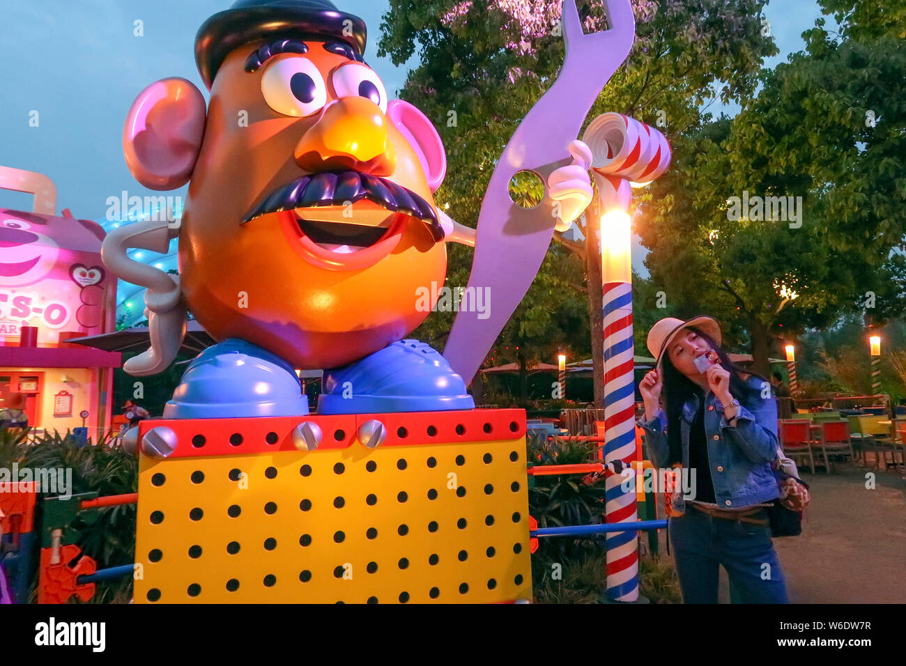 Ein Besucher stellt für Fotos mit einer Skulptur von Frau Potato Head, ein Charakter der animierte Film Pixars "Toy Story", an der 7. Thematische Land, Disney Stockfoto