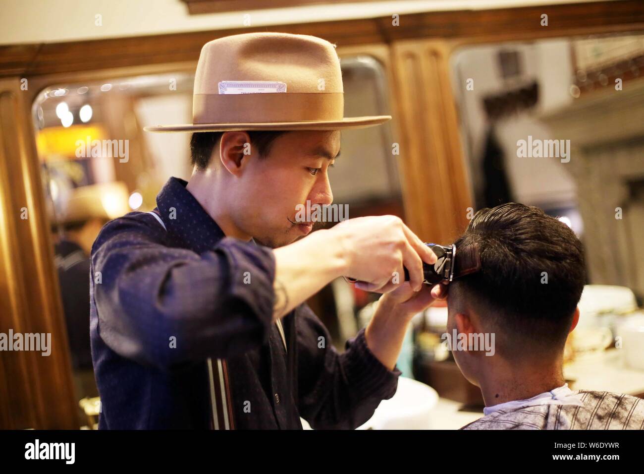 Der Besitzer eines Shanghai-based Barbershop, BarberShop nur auf vintage Herren- Stil Haarschnitte arrangiert ein retro Frisur für einen Kunden in Stockfoto