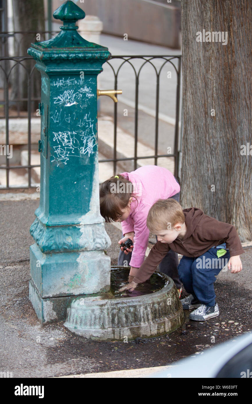 Wasser erkunden. Zwei Kinder der Trog mit Wasser unter den Trinkbrunnen erkunden Stockfoto