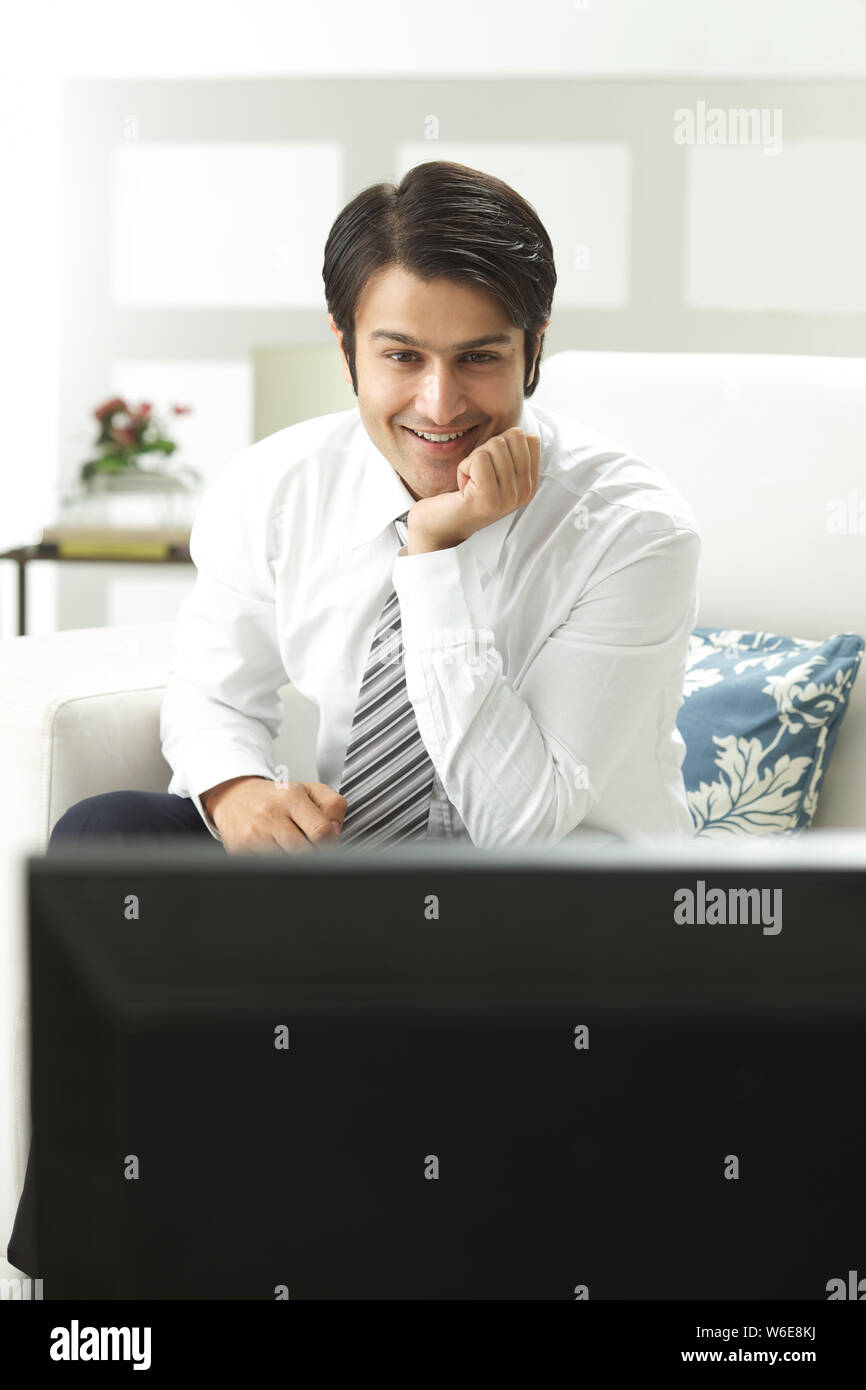 Geschäftsmann, der zu Hause Fernsehen schaut Stockfoto