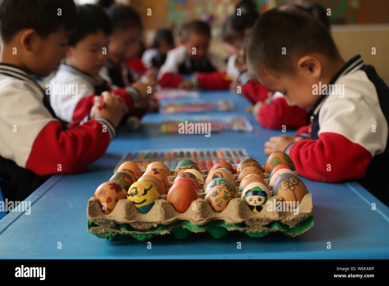 Kinder zeigen Eier mit chinesischen Zeichen und Farben auf den Tag der "Chunfen' (Frühlingspunkt oder Tagundnachtgleiche) in einem Kindergarten im Bin mark Stockfoto
