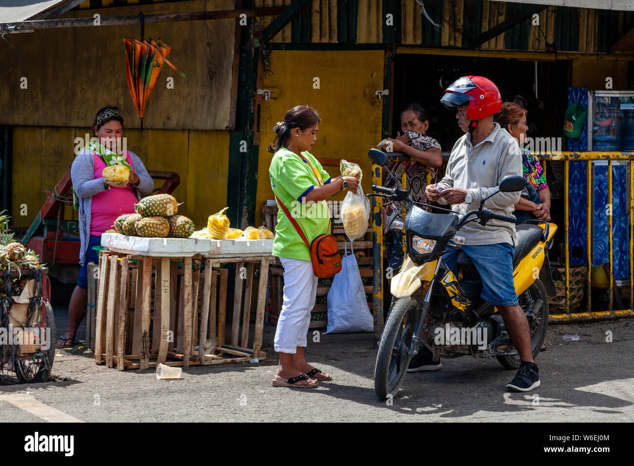 Ein Mann auf einem Motorrad kaufen Frisch Geschnittene Ananas, CO2-Markt, Cebu City, Cebu, Philippinen Stockfoto