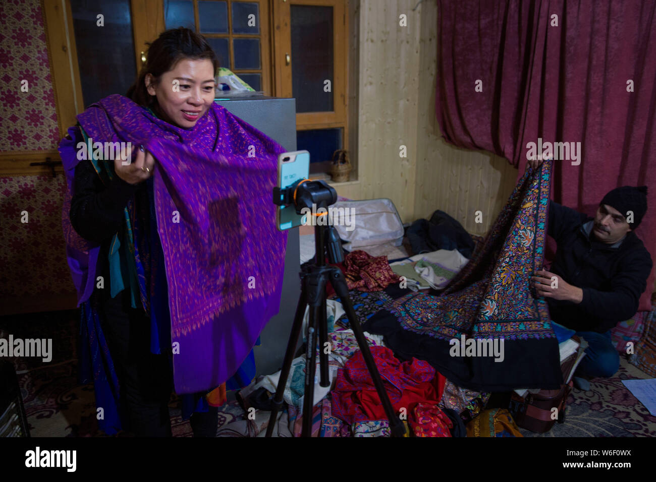 ------ Chinesische Frau mit dem Beinamen Yao macht live streaming webcast Kaschmir Schals von Handwerker mit den traditionellen Fertigkeiten in Kaschmir Region zu fördern, Stockfoto