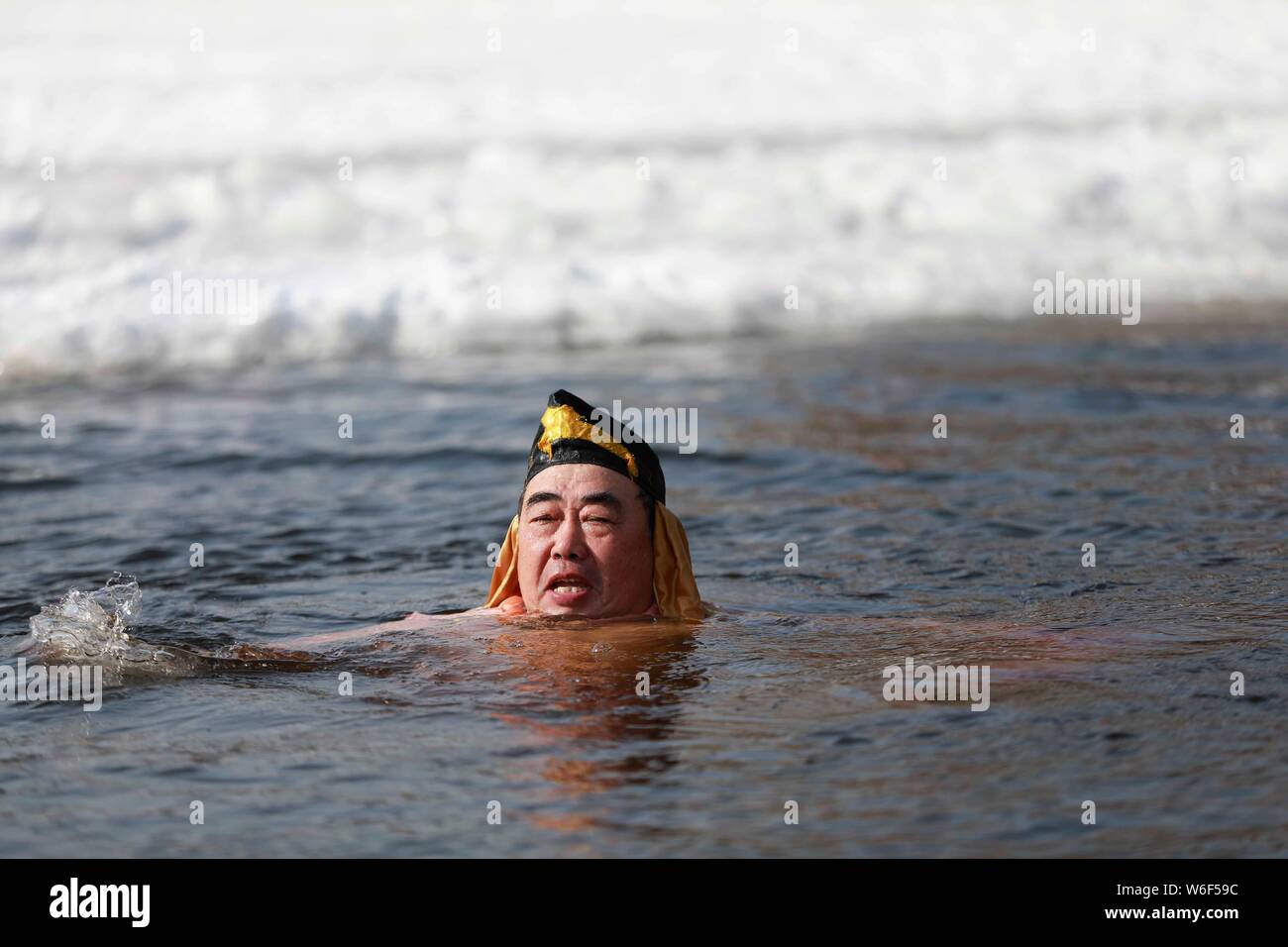 Eine chinesische Winter schwimmen Enthusiasten in das Kostüm von Zhu Bajie, einem wichtigen Charakter des Romans die Reise nach Westen gekleidet, führt lustig Tauchen in Stockfoto