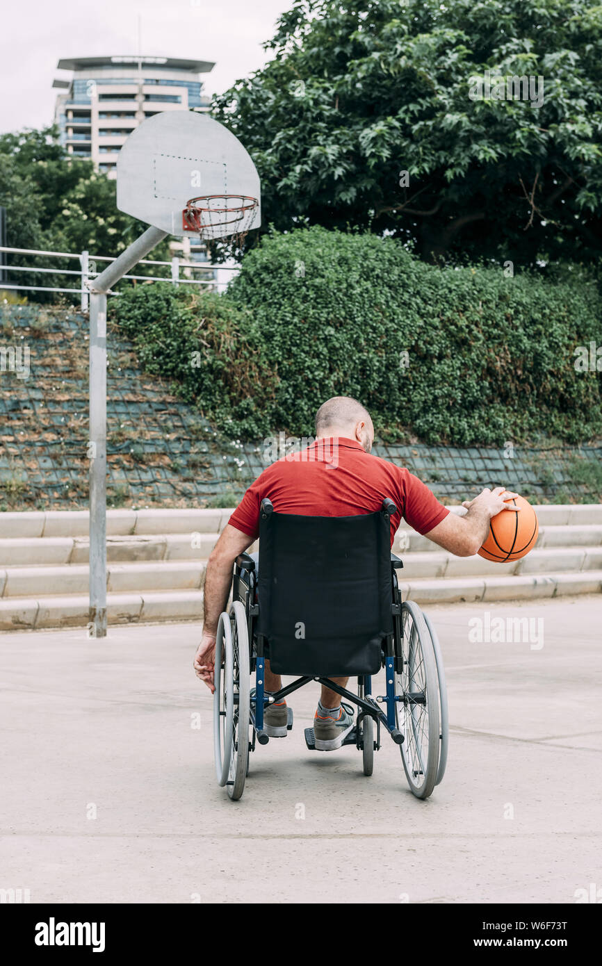 Behinderte Menschen im Rollstuhl Basketball allein spielen in der Stadt, das Konzept der adaptiven Sport und körperliche Aktivität, Rehabilitation für Menschen mit Phys Stockfoto
