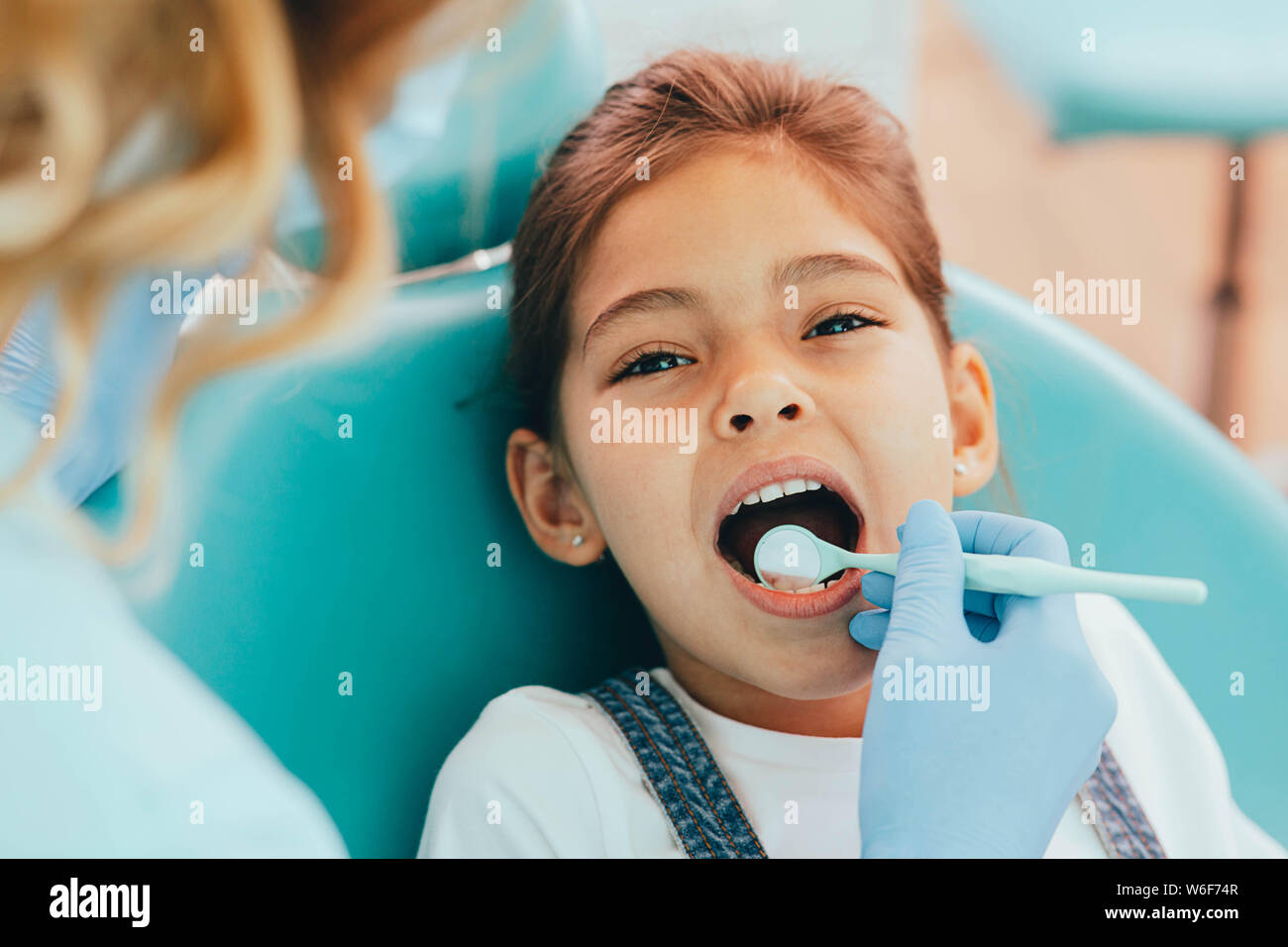 Gemischte Rasse Mädchen erhalten Ihre Zähne mit zahnmedizinischer Spiegel geprüft Stockfoto