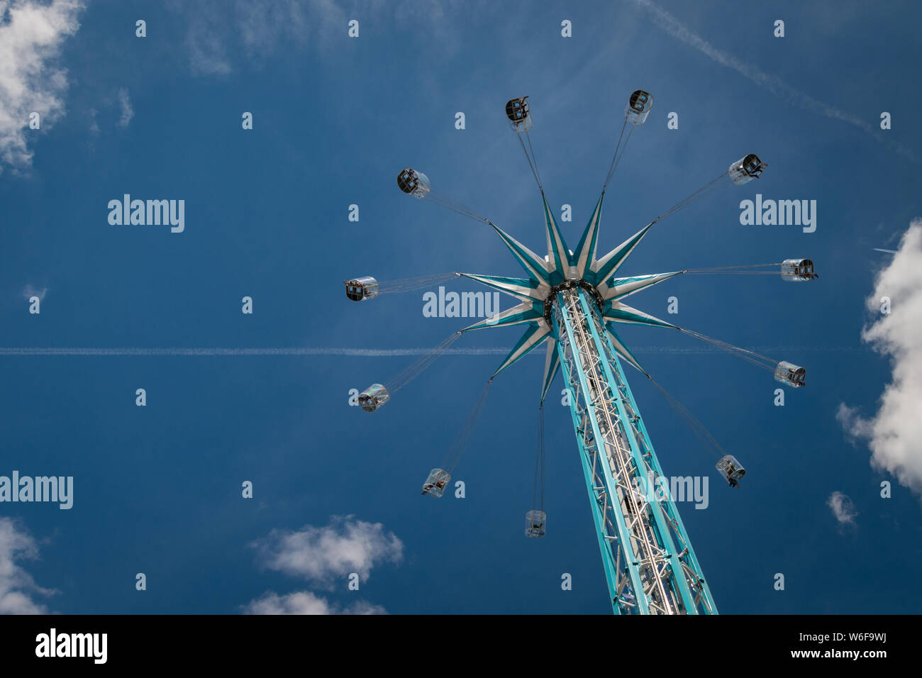 Fahrgeschäft auf chairoplane mit fliegenden Menschen vor einem Blauen und bewölkter Himmel Stockfoto