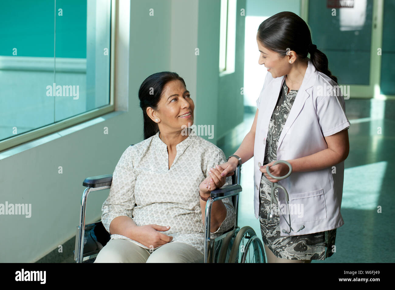 Ärztin im Gespräch mit einer Patientin, die im Rollstuhl sitzt Stockfoto