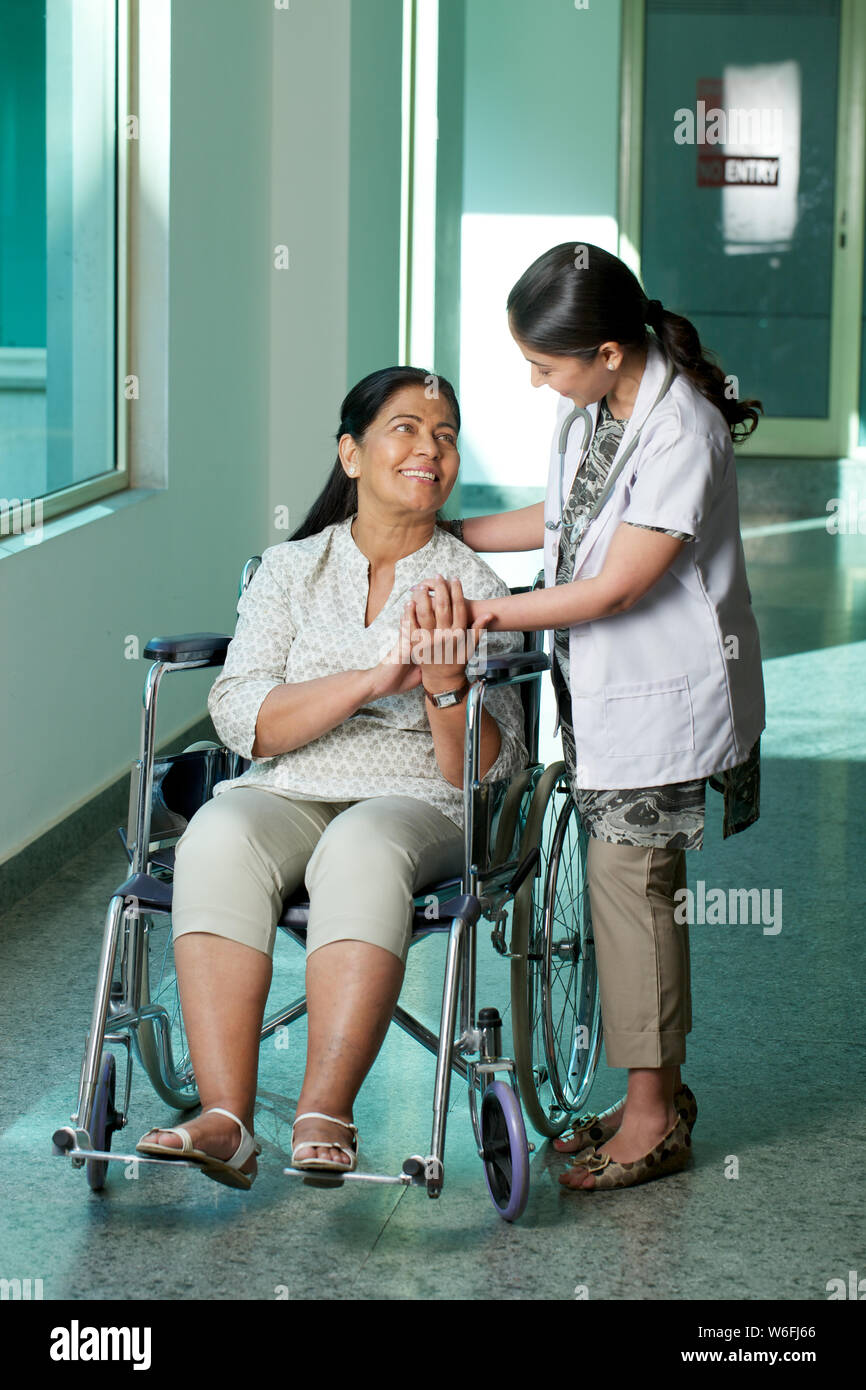 Ärztin im Gespräch mit einer Patientin, die im Rollstuhl sitzt Stockfoto