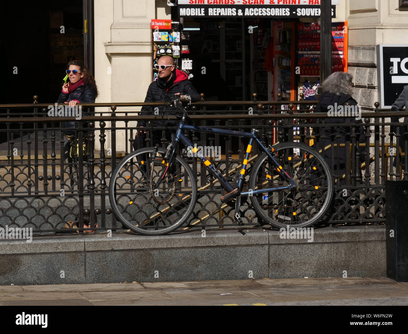 Fahrrad angekettet auf dem Geländer der Ein- und Ausfahrt von der Piccadilly Circus U-Bahn in London, an einem sonnigen Tag im März. Stockfoto