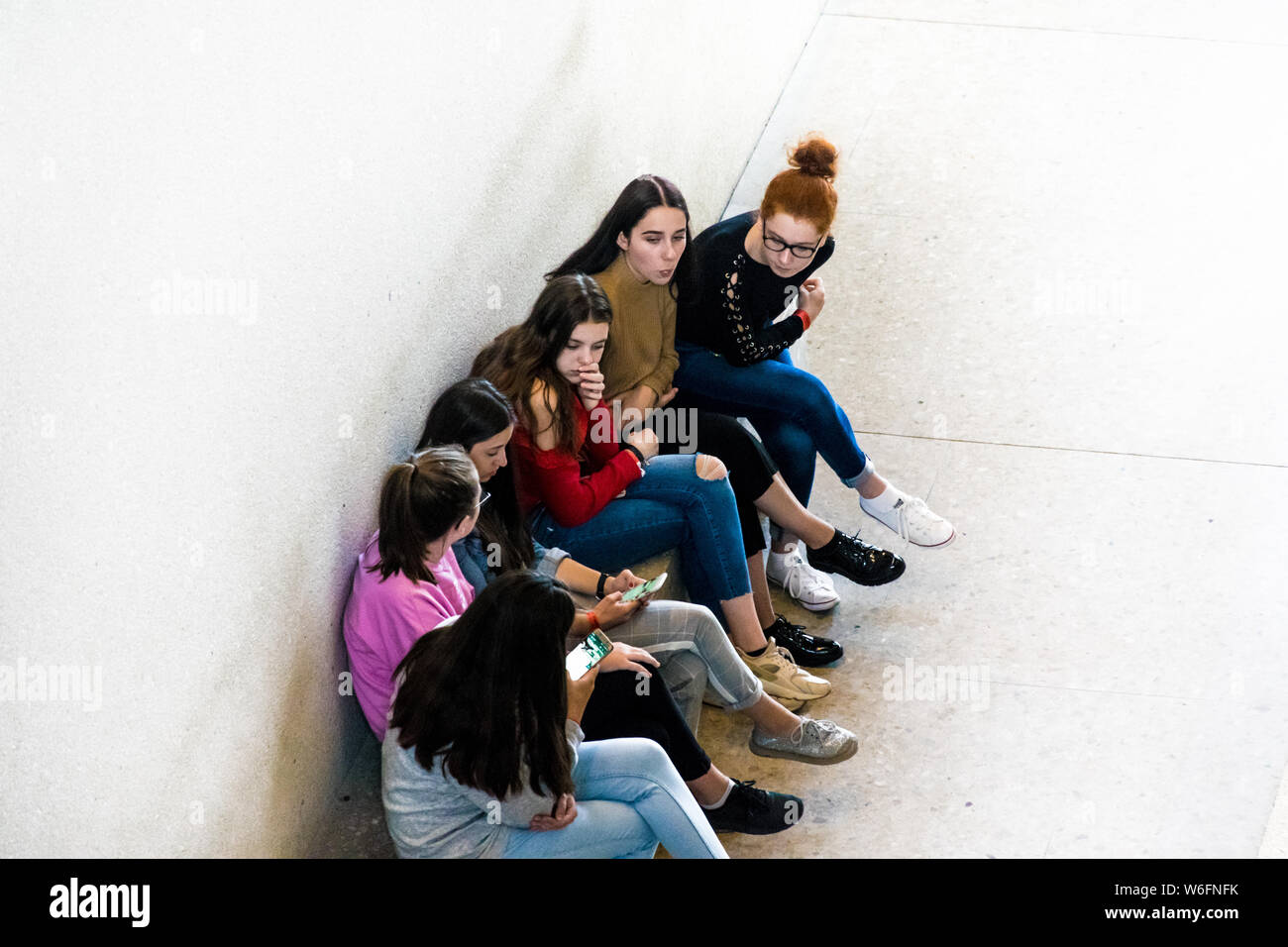 BERLIN, DEUTSCHLAND - 26. SEPTEMBER 2018: in, nach unten Perspektive einer Gruppe von Mädchen, die auf ihren Smartphones während einer Steinbank sitzend Gezoomt Stockfoto