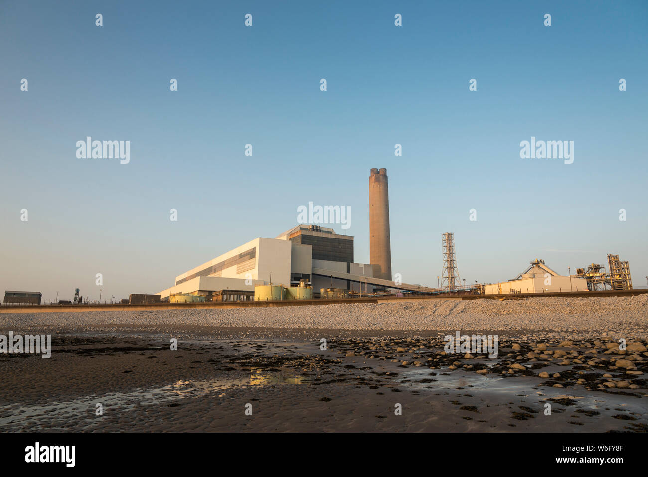 Ein Blick auf die Kohle Kohlekraftwerk Aberthaw, von den angrenzenden Strand, wenn es in blassen Abendsonne unter einem wolkenlosen blauen Himmel gebadet. Stockfoto