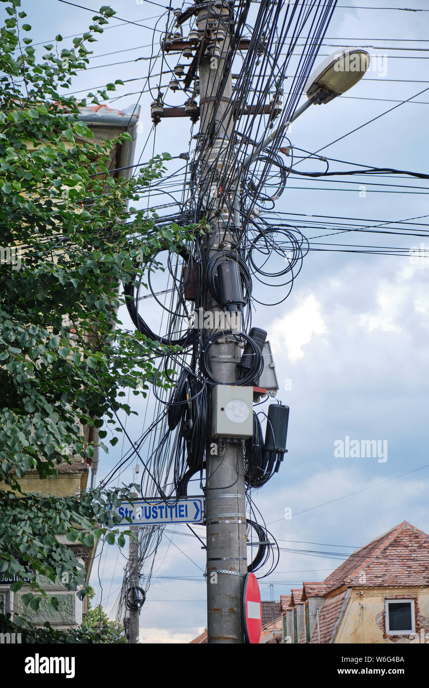 Straße Pol mit TV, Internet, Telefonie, Strom und Kabel hängend in einer unorganisierten Materie - in Justice Street (Strada Justitiei) in Si Stockfoto