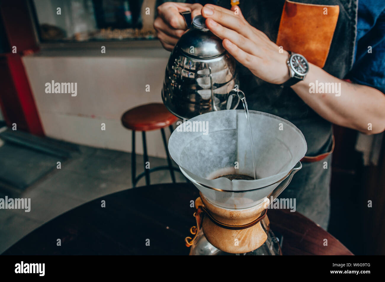 Barista Vorbereitung filter Kaffee im Freien. Männliche barista gießt kochendes Wasser aus dem Wasserkocher Stockfoto