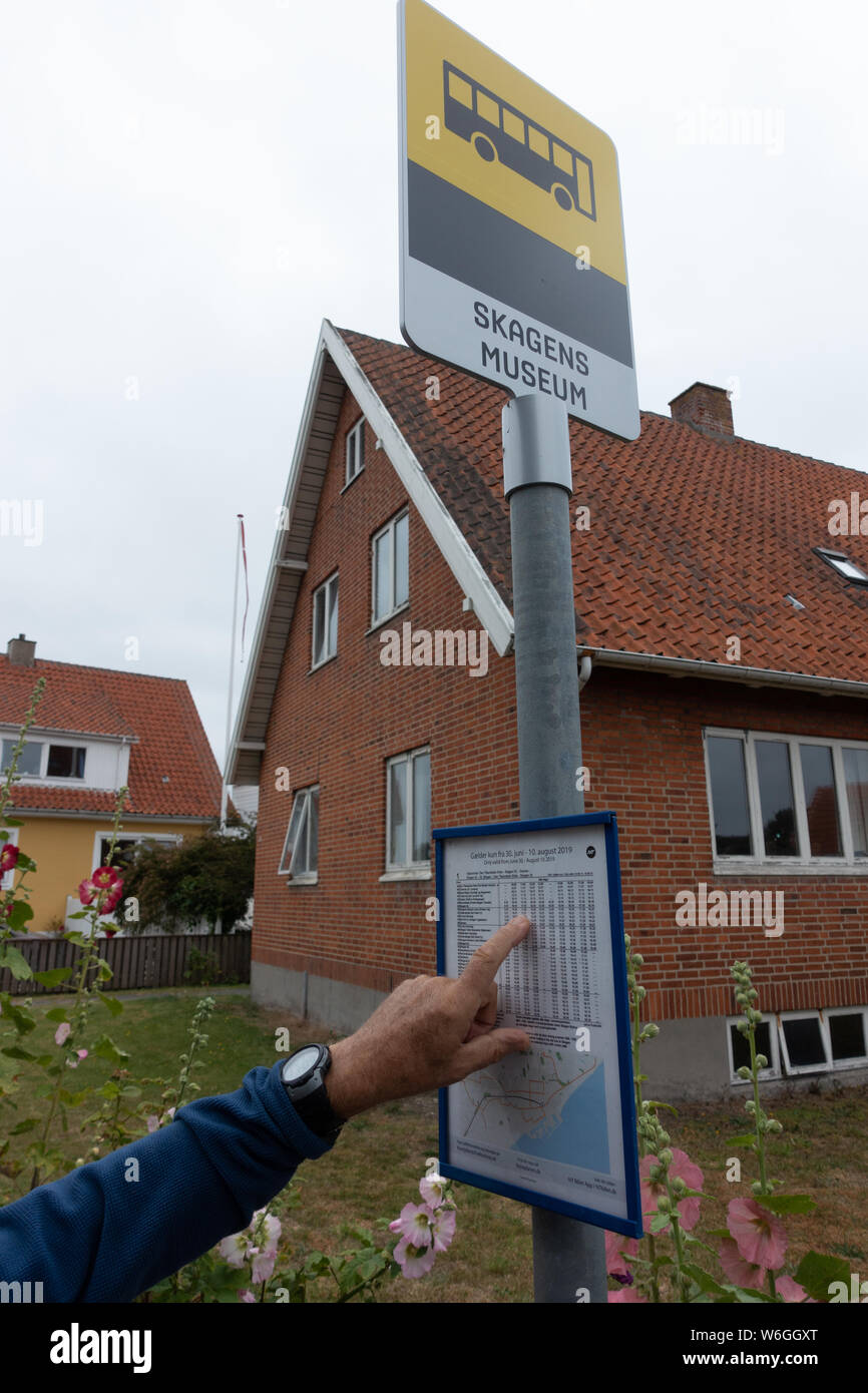 Zwei Besucher in Skagen an einem Bus Fahrplan suchen Stockfoto