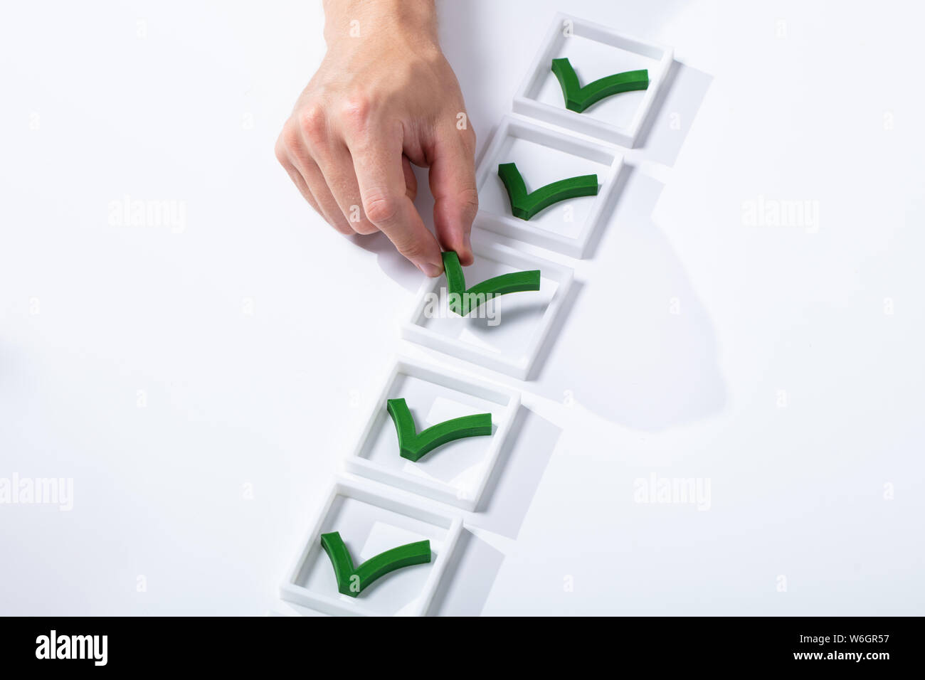 Hohe Betrachtungswinkel des Mannes Hand grüne Markierung in Feld mit weißem Hintergrund prüfen Stockfoto